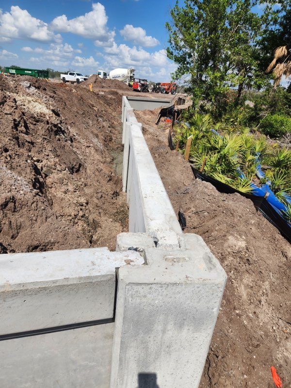 Precast concrete retaining wall base installation foundation prep Florida