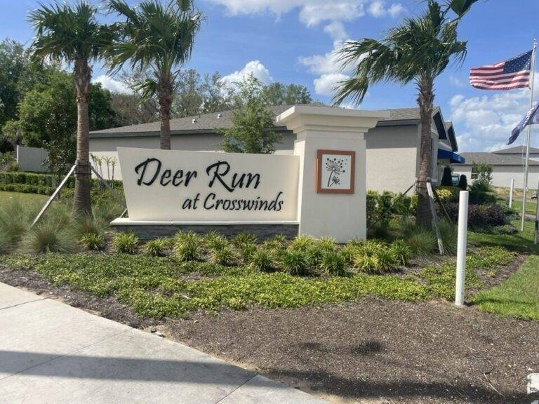 Monument sign with stone pillar and American flag at Deer Run Crosswinds entrance Florida