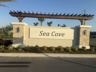 pergola-monument-sign-sea-cove-florida Brown pergola monument sign with stacked stone and wall lanterns Sea Cove Florida
